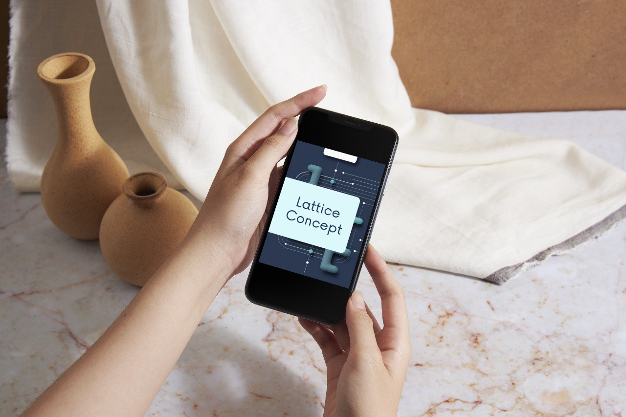 A person holds a smartphone showing a digital design template with the text 'Lattice Concept' on the screen, set against a styled background of terracotta vases, draped cream fabric, and a marble surface.