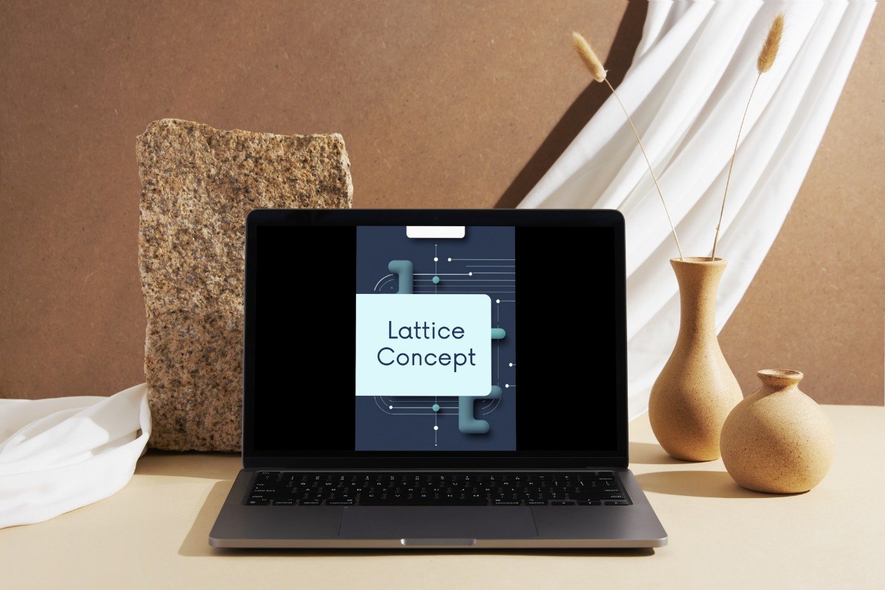 A dark gray laptop sits open on a beige tabletop, displaying a digital graphic with the text 'Lattice Concept' on its screen. The setup is styled with a textured stone block, white draped fabric, and two beige ceramic vases in the background against a warm brown wall.